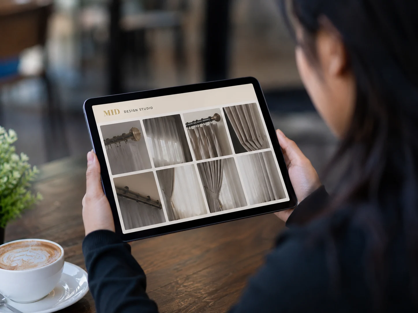 Woman browsing curtain style options on a tablet at a café