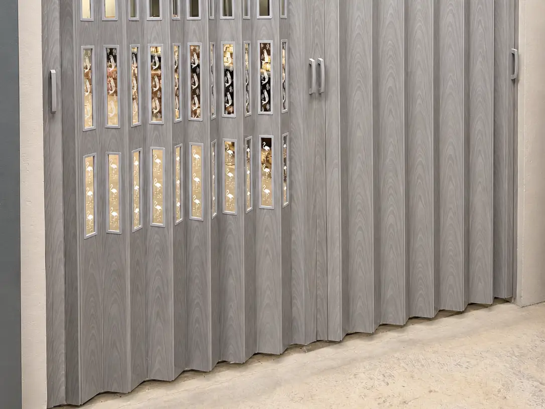 Grey wood-grain accordion room divider with decorative flamingo panel inserts