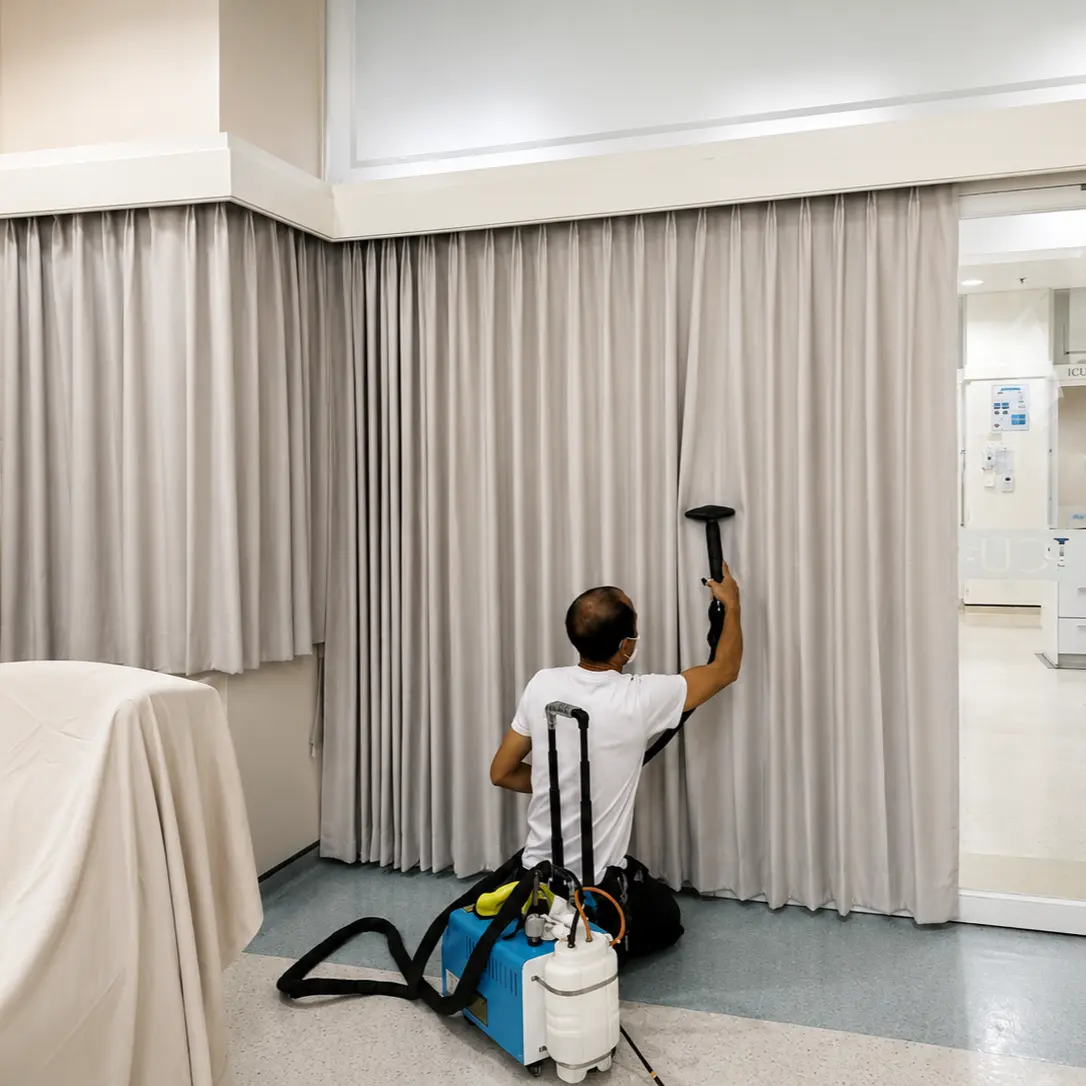 Technician steam-cleaning curtains on-site