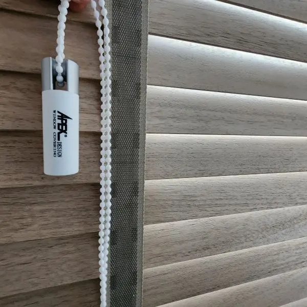 Close-up of a wood venetian blind's pull chain and control wand against the slats