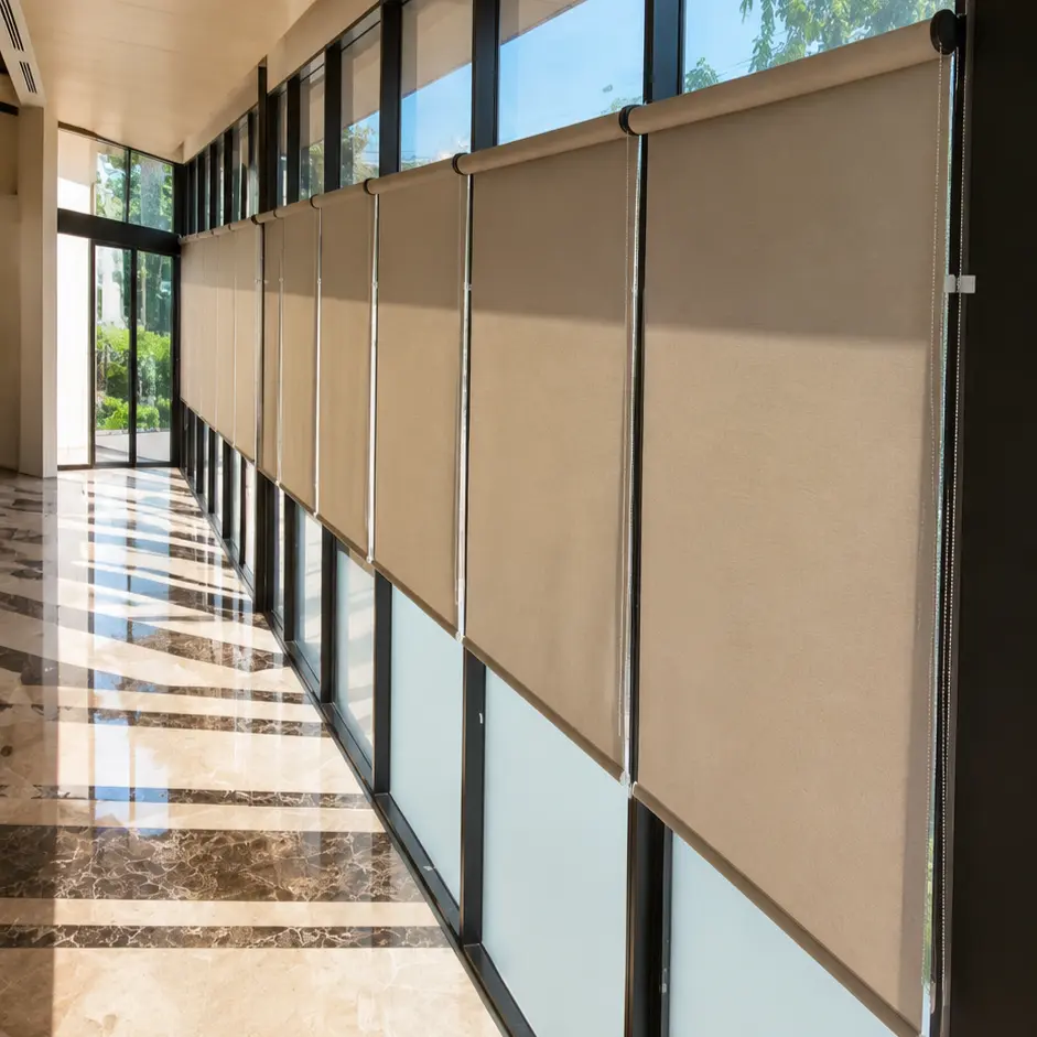 Marble-floored corridor with a row of taupe roller blinds lowered along floor-to-ceiling windows