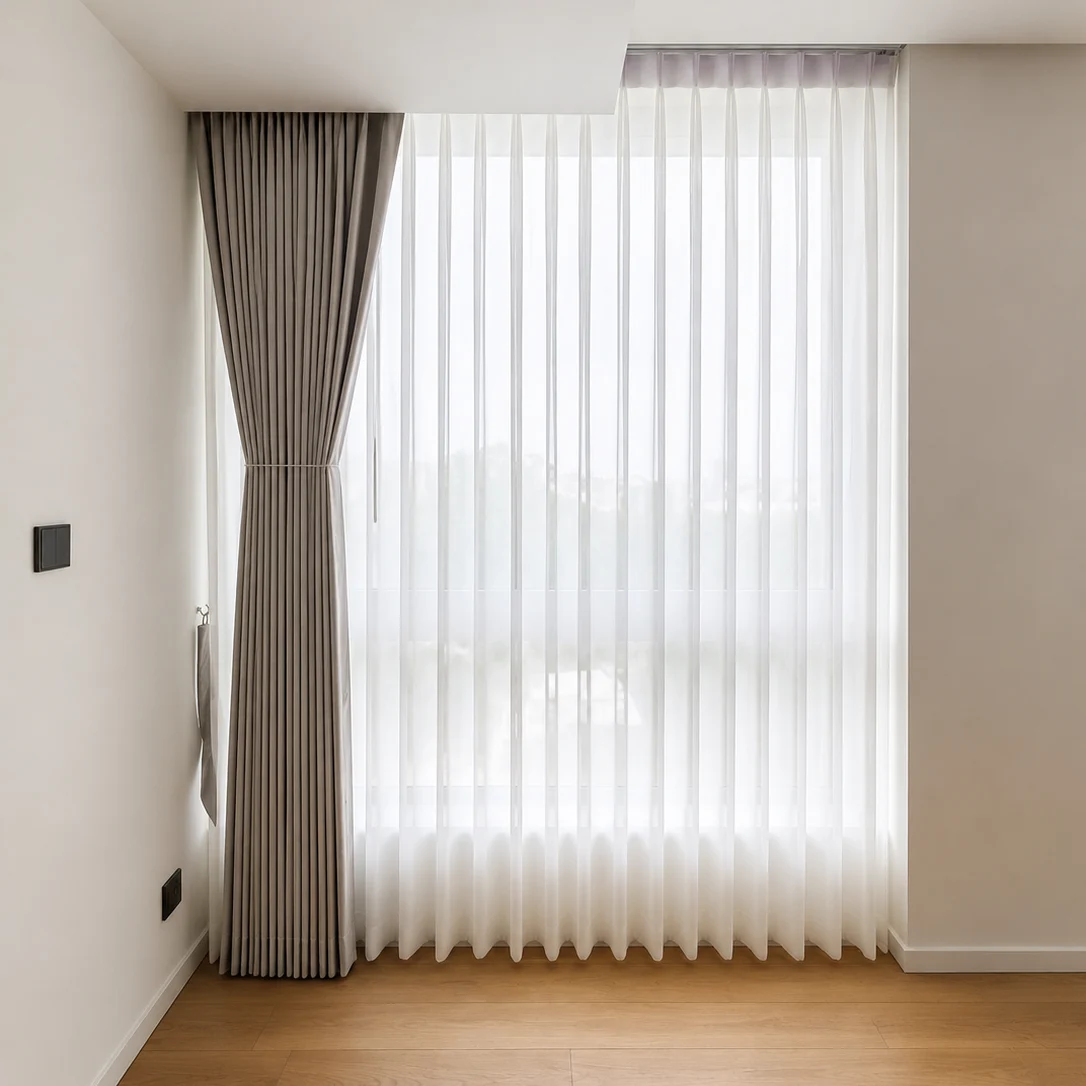 Bedroom corner with floor-to-ceiling sheer wave-fold curtains and a taupe tieback drape beside a wardrobe