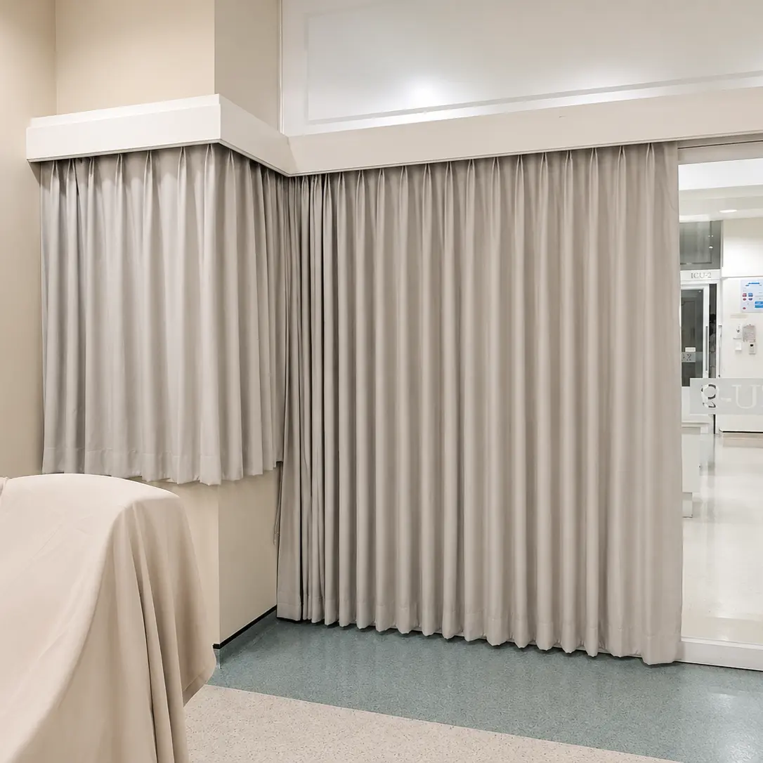 Hospital room with pleated privacy curtains open beside a sliding glass door to the corridor