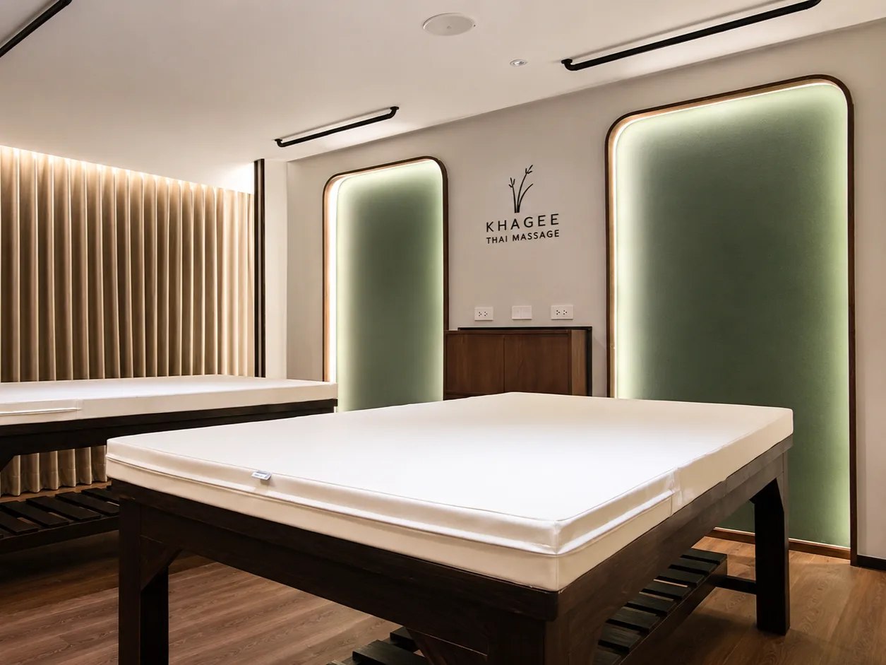 Thai massage spa treatment room with cream pleated curtains along the back wall and two treatment beds