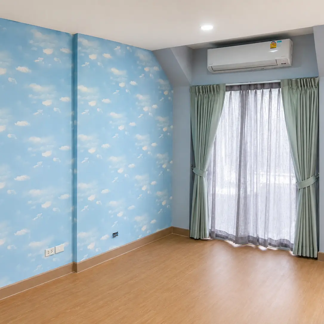 Blue sky and cloud pattern wallpaper in a bedroom with sheer green curtains