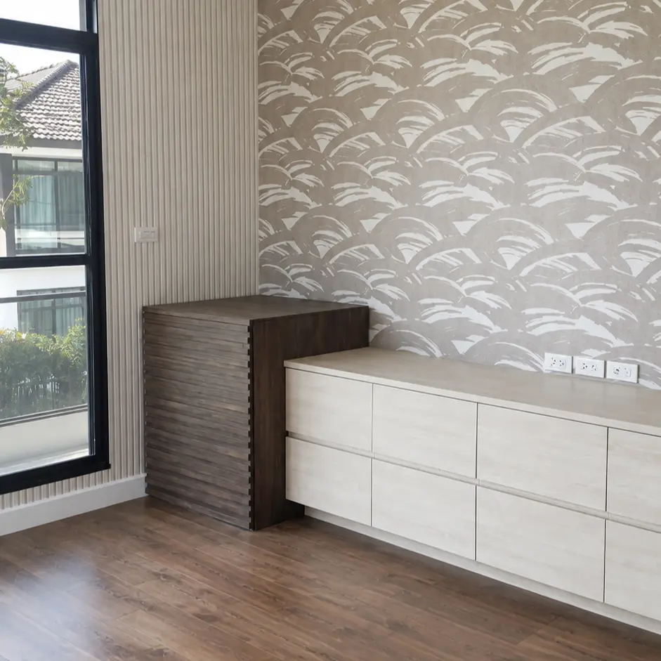 Taupe scalloped wave pattern wallpaper above a built-in cabinet with wood flooring
