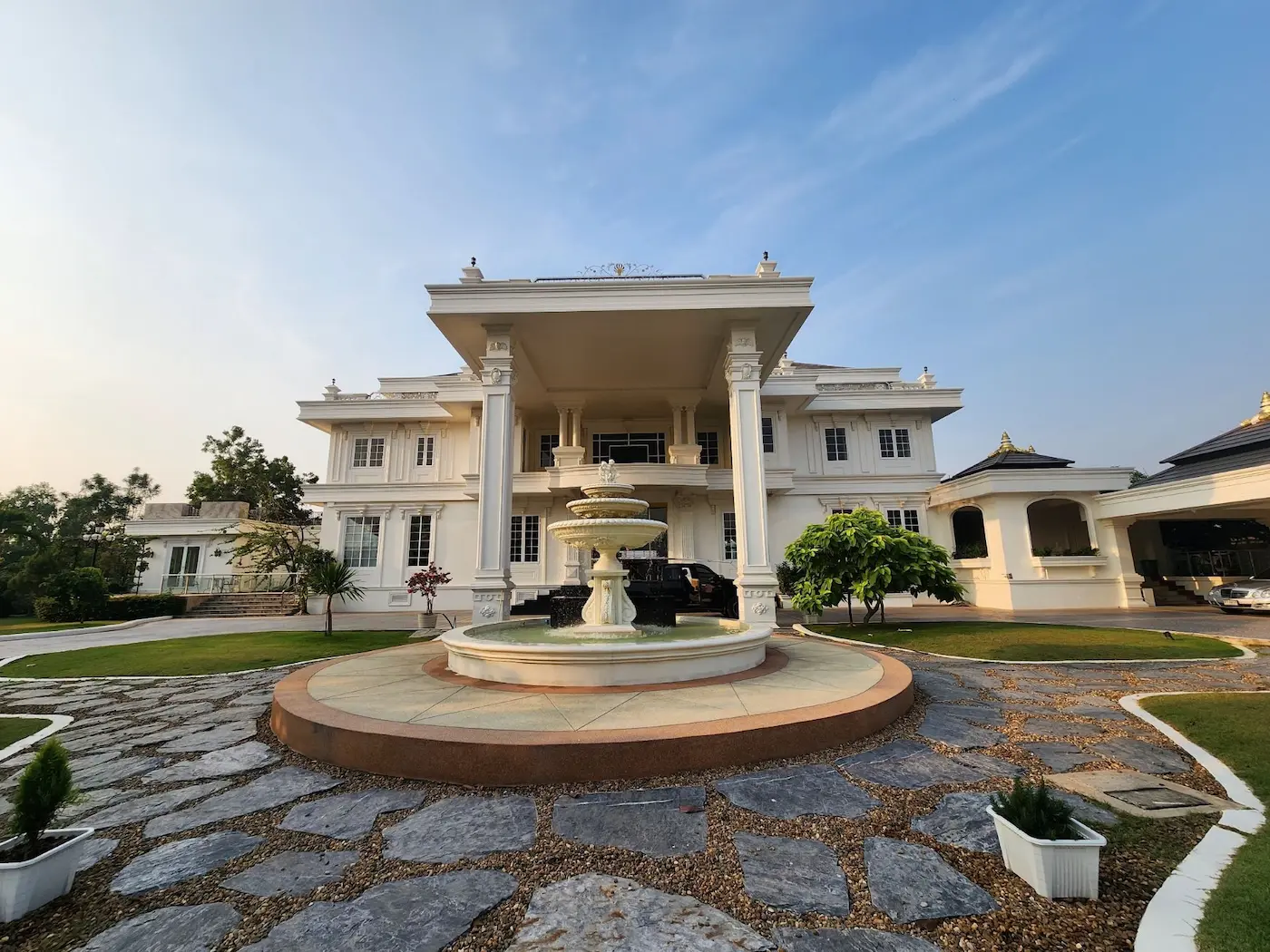 Two-story neoclassical house with columned entrance and a fountain in the circular driveway, Bang Na project
