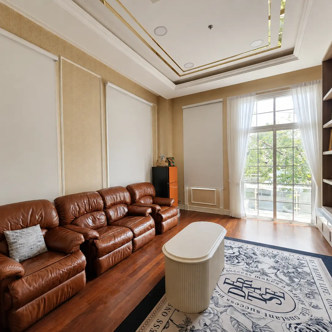 Living room with leather sofa, roller blinds and sheer curtains at the balcony door