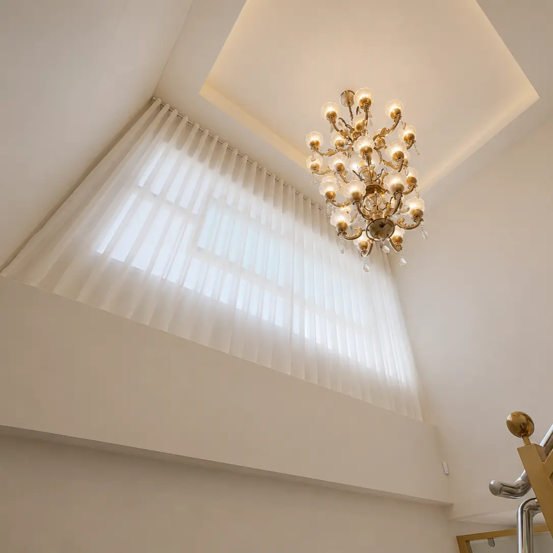 Double-height stairwell with crystal chandelier and sheer wave curtains