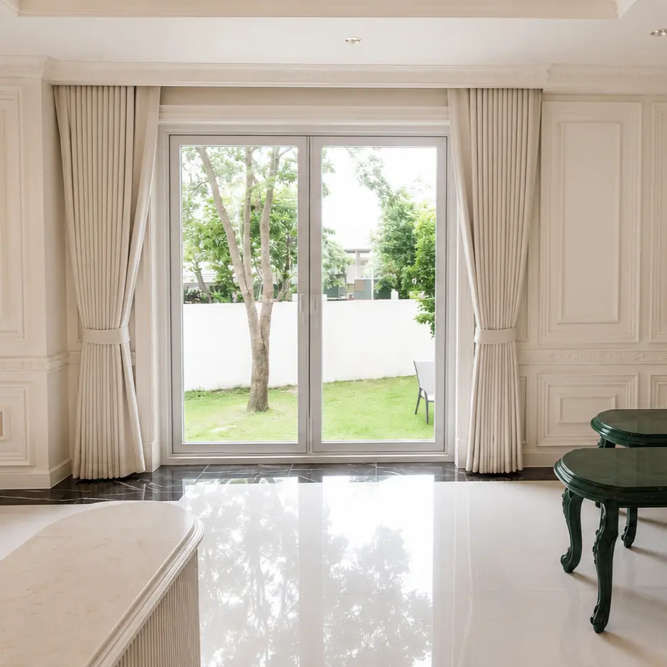 White paneled living room with glass garden door and dark green side tables