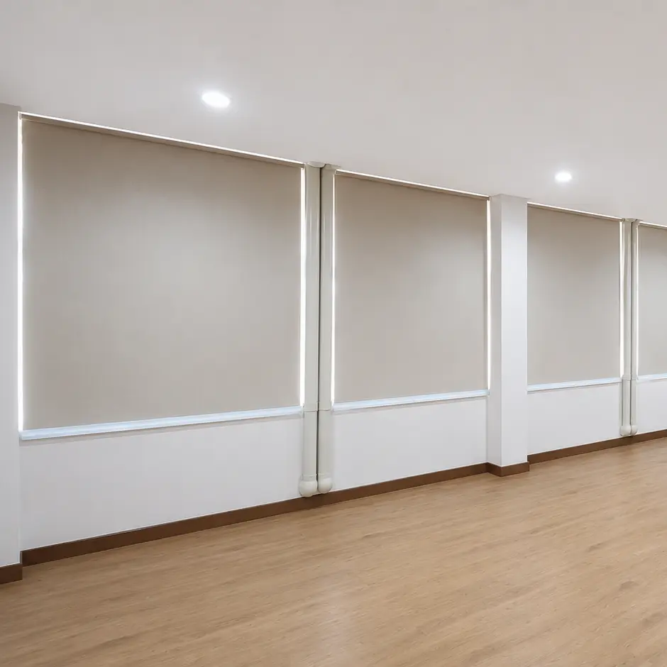 Wide view of an empty room with four closed roller blinds along one wall