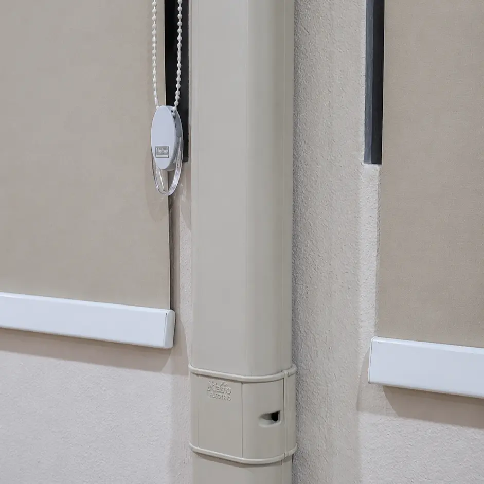 Close-up of roller blind bead chain and control clutch beside a wall-mounted air conditioning unit