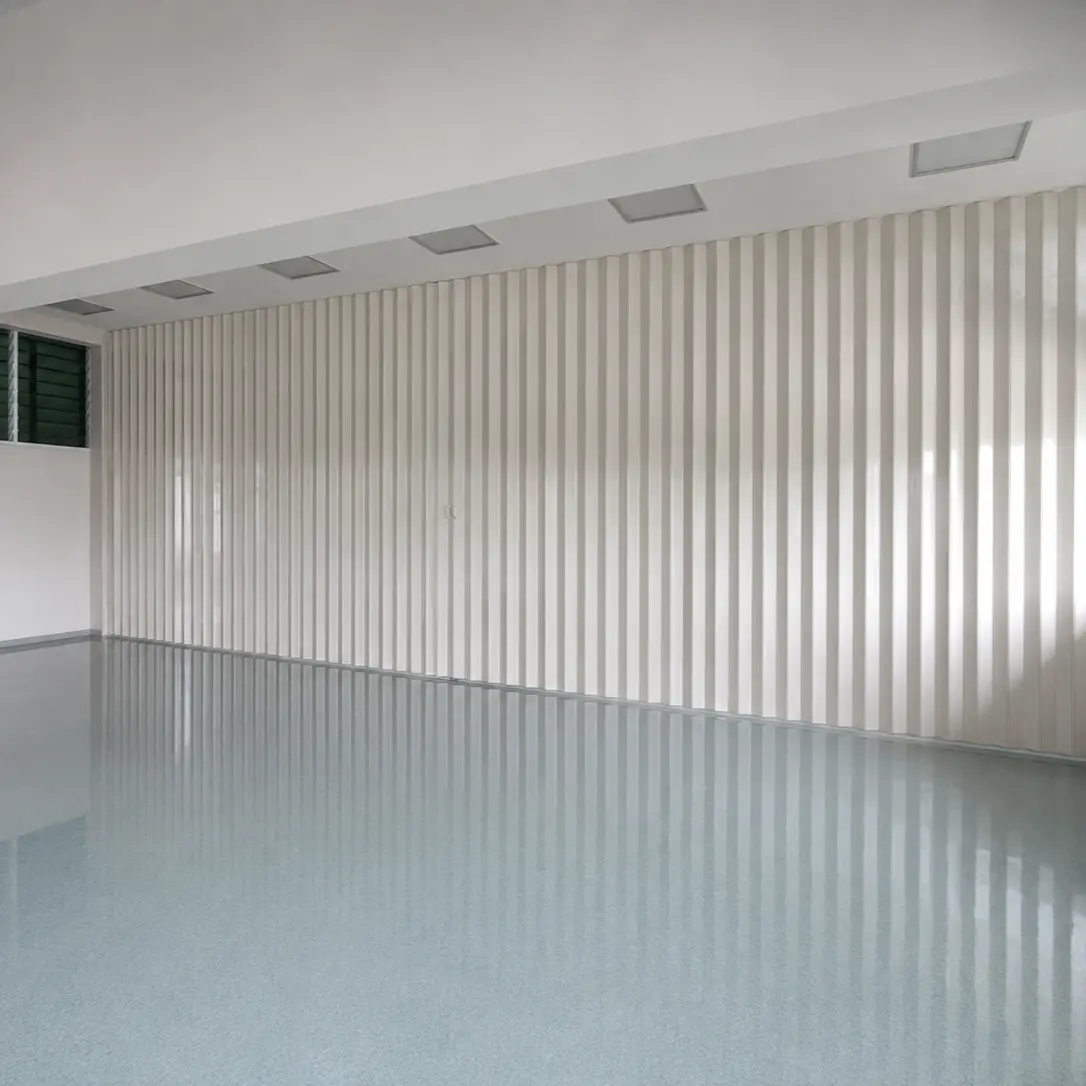 Empty university room with a white fluted accordion room divider along the back wall and glossy terrazzo flooring