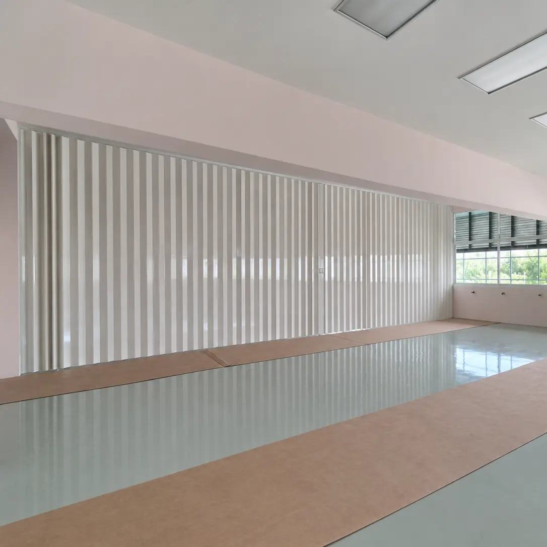 Classroom with a white fluted accordion room divider partially closed and floor protection sheeting