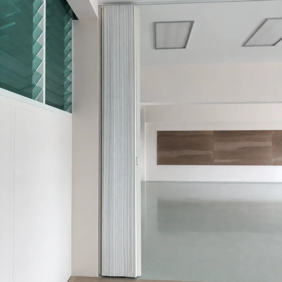 Close-up of a white fluted accordion room divider folded closed against a wall