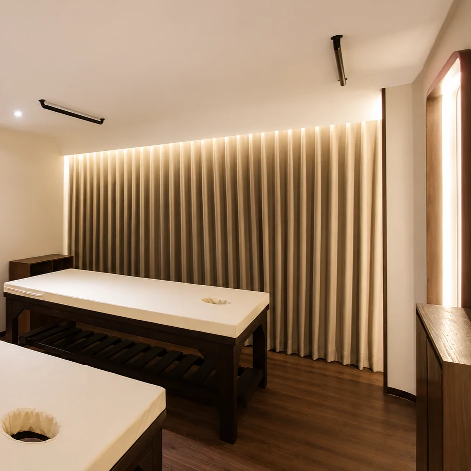 Treatment room with a freestanding bathtub, wood-slat wall paneling and floor-to-ceiling curtains