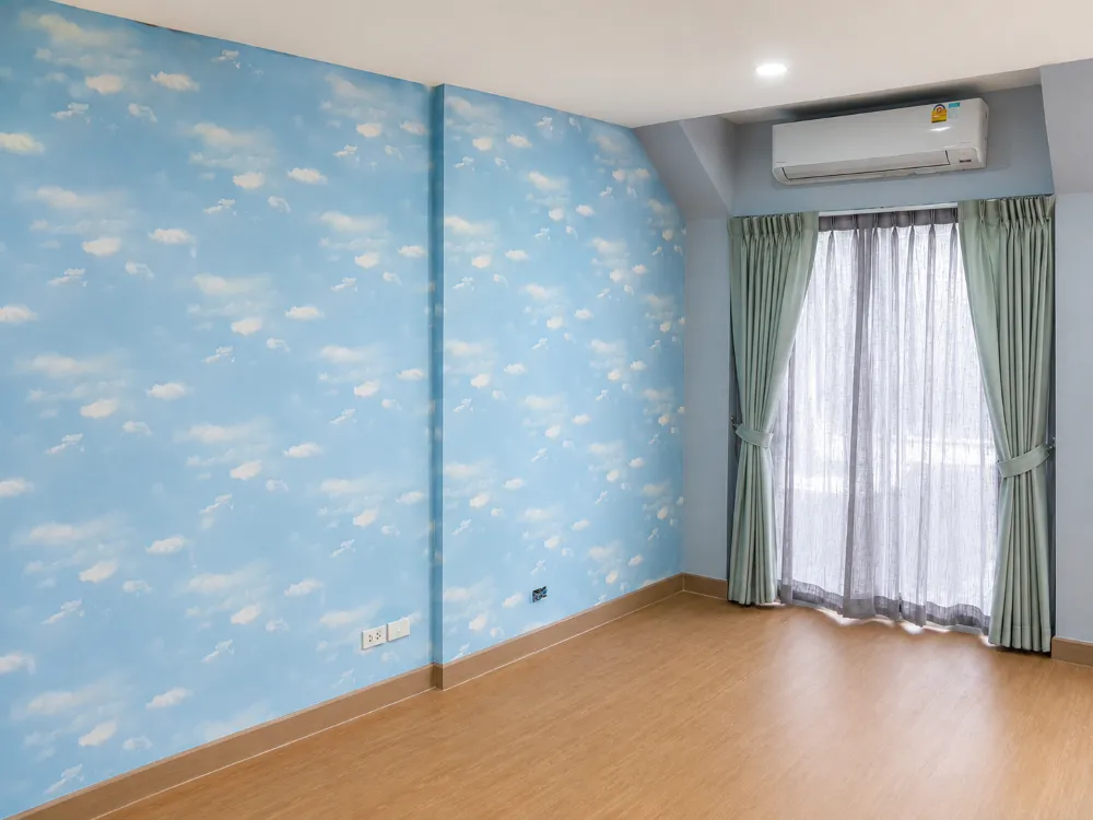 Blue sky and cloud pattern wallpaper in a bedroom with sheer green curtains