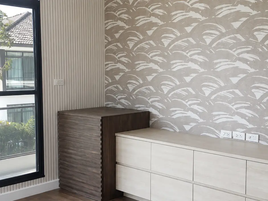Taupe scalloped wave pattern wallpaper above a built-in cabinet with wood flooring